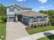 Beautiful two-story home featuring a manicured lawn and a paver driveway on a sunny day at 18219 Ramble On Way, Land O Lakes, FL 34638