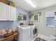 Well-lit laundry room with modern washer and dryer, storage cabinets, and stylish decor at 18219 Ramble On Way, Land O Lakes, FL 34638