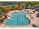 Aerial view of a large community pool with a slide, splash pad, and ample seating surrounded by lush landscaping at 19407 Sweet Grass Way, Lutz, FL 33558