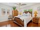 Bedroom features a wooden bed frame, ceiling fan, hardwood floors, and natural lighting at 206 Corbett St, Belleair, FL 33756