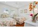 Bright bedroom with twin beds, floral bedding, and a white wicker bedside table at 206 Corbett St, Belleair, FL 33756