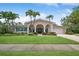 Charming home with a well-manicured lawn and palm trees, offering a welcoming curb appeal and architectural detail at 206 Corbett St, Belleair, FL 33756