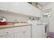 Functional laundry room with white cabinets, sink, and modern washer and dryer at 206 Corbett St, Belleair, FL 33756