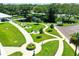 Aerial view of a community park with walking paths, picnic tables, a pond, and lush greenery at 2231 Utopian E Dr # 117, Clearwater, FL 33763