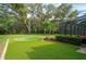 Beautiful backyard featuring a putting green, lush landscaping, and screened in patio with serene views at 2680 Keystone Springs Rd, Tarpon Springs, FL 34688