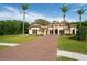 Beautiful Mediterranean-style home with a brick driveway, lush lawn, and towering palm trees on a sunny day at 2680 Keystone Springs Rd, Tarpon Springs, FL 34688