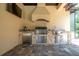 Outdoor kitchen featuring stone accents, built-in grill, sink, mini-refrigerator and stainless steel cabinetry at 2680 Keystone Springs Rd, Tarpon Springs, FL 34688