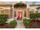 Charming home entrance with a bright red door, stone accents, and lush landscaping at 27338 Hollybrook Trl, Wesley Chapel, FL 33544