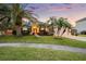 Charming single-Gathering home features a well-manicured lawn, mature palm trees, and a red front door at 27338 Hollybrook Trl, Wesley Chapel, FL 33544