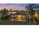 Exterior view showcases a screened pool at dusk, palm trees, and lush backyard setting at 27338 Hollybrook Trl, Wesley Chapel, FL 33544