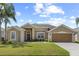 Charming home exterior with a well-manicured lawn, mature landscaping, and a two-car garage at 29432 Coharie Loop, San Antonio, FL 33576