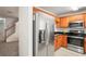 Kitchen with stainless steel refrigerator, oak cabinetry, black countertops, and a glimpse of carpeted stairs at 3437 Dragon View Ct, Valrico, FL 33594