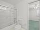 All-white bathroom with a glass shower door, toilet and doorway leading to the bedroom at 4033 Priory Cir, Tampa, FL 33618