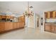 Spacious kitchen featuring tile flooring, wood cabinets, granite countertops, and elegant chandelier at 4033 Priory Cir, Tampa, FL 33618