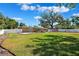 Spacious backyard with lush green lawn, mature trees, white fence, and covered patio at 505 S Larry Cir, Brandon, FL 33511
