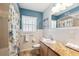 Bathroom featuring a granite countertop vanity, a bathtub with floral shower curtain, and blue accent wall at 505 S Larry Cir, Brandon, FL 33511