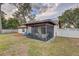 View of the backyard with a screened-in patio, outdoor seating, and a well-maintained lawn at 614 Sandalwood Dr, Plant City, FL 33563