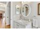 Bright bathroom with white vanity, marble countertop, round mirror, and wood flooring at 614 Sandalwood Dr, Plant City, FL 33563