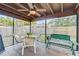 Cozy screened-in porch with fan, table, chairs, and a bench for relaxing in the shade at 614 Sandalwood Dr, Plant City, FL 33563