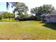 Expansive backyard with lush lawn, mature trees, and a view of the house and screened-in lanai at 63 Forest Wood Ct, Spring Hill, FL 34609
