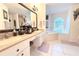 Bright bathroom featuring dual sinks, makeup vanity, large mirror, and a soaking tub near arched window at 63 Forest Wood Ct, Spring Hill, FL 34609