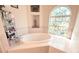 Bright bathroom with soaking tub with tile surround near an arched decorative window at 63 Forest Wood Ct, Spring Hill, FL 34609