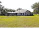 An exterior shot of the back of the house showing the screened-in lanai and lush green lawn at 63 Forest Wood Ct, Spring Hill, FL 34609