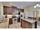 Well-equipped kitchen with stainless steel appliances, dark wood cabinetry, granite counters, and tile flooring at 6918 Frog Pocket Pl, Tampa, FL 33616