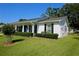 Charming one-story white brick home featuring manicured bushes and a pop of color from the front door at 7229 Northbridge Blvd, Tampa, FL 33615