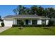 Charming single-story home with a manicured lawn, vibrant blue front door, and attached garage, offers classic curb appeal at 7229 Northbridge Blvd, Tampa, FL 33615