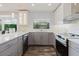 Modern kitchen boasts two-tone cabinetry, a garden view window, stainless steel appliances, and stylish lighting at 7402 America Way, New Port Richey, FL 34654