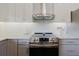 Updated kitchen features stainless steel appliances, a modern range hood, and sleek countertops with ample cabinet space at 7402 America Way, New Port Richey, FL 34654
