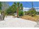 Wide gravel driveway, secured gate, and a quaint home featuring mature palm trees and landscaping at 850 Center Ave, Brandon, FL 33511