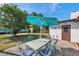 Outdoor patio complete with a metal table, chairs, and a large turquoise umbrella to provide shade at 9010 Bonnet Way, Weeki Wachee, FL 34613
