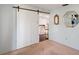 Bedroom with modern barn door, neutral carpet, and access to a stylish kitchen area at 9010 Bonnet Way, Weeki Wachee, FL 34613
