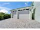 A spacious two-car garage featuring white doors, exterior lighting, and a paved driveway, adding convenience and curb appeal at 935 Chipaway Dr, Apollo Beach, FL 33572