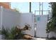 White backyard gate entrance surrounded by lush greenery and a decorative hanging basket at 9950 47Th N Ave # 311, St Petersburg, FL 33708