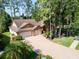 Aerial view of home with long driveway and three-car garage, set among lush trees at 10 Greenhaven Cir, Oldsmar, FL 34677
