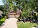 Aerial view of home with brick driveway, a well-manicured lawn, and mature trees at 10 Greenhaven Cir, Oldsmar, FL 34677