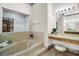 A bathroom features a soaking tub with tile detail, plus a vanity area with stool for comfort and convenience at 10 Greenhaven Cir, Oldsmar, FL 34677