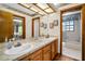 Bathroom features double sinks with wood cabinets and a view to the shower, blending functionality with classic design elements at 10 Greenhaven Cir, Oldsmar, FL 34677