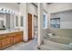 A bathroom showcasing a soaking tub with a tile surround, complemented by warm wood cabinets and natural light at 10 Greenhaven Cir, Oldsmar, FL 34677
