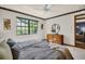 Bright bedroom features large window, ceiling fan and dresser with round mirror at 10 Greenhaven Cir, Oldsmar, FL 34677