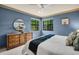 Cozy blue bedroom with bright windows, ceiling fan, dresser, and round mirror at 10 Greenhaven Cir, Oldsmar, FL 34677