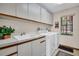 Bright laundry room features built in cabinets, sink, and a window at 10 Greenhaven Cir, Oldsmar, FL 34677