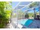 Screened-in pool with a blue interior, set amid lush tropical foliage with blue skies above at 10918 Lake Andover Blvd, Tampa, FL 33624
