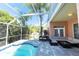 View of the pool and lanai, including outdoor seating and lush landscaping and clear blue skies at 10918 Lake Andover Blvd, Tampa, FL 33624