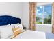 Bright bedroom showcases a tufted headboard bed and a window view with decorative curtains at 11 Franklin S Ct # C, St Petersburg, FL 33711
