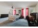 Spacious bedroom featuring a ceiling fan, gray carpet, and a comfortable bed with red and white curtains at 11802 Foxrun Ln, Temple Terrace, FL 33617