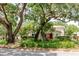 Beautiful home exterior with mature trees, lush landscaping, and a vibrant red front door at 11802 Foxrun Ln, Temple Terrace, FL 33617